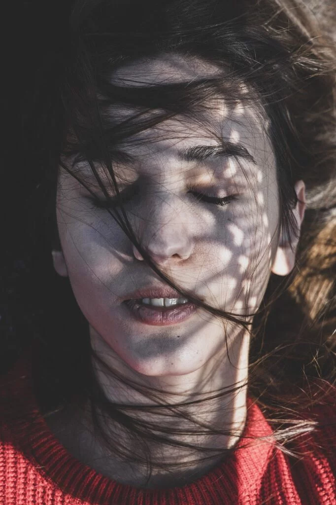 A young woman sits peacefully with her eyes closed, symbolizing inner healing and calmness, representing emotional recovery through hypnotherapy.